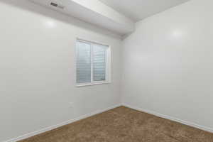 Empty room with dark colored carpet and baseboards