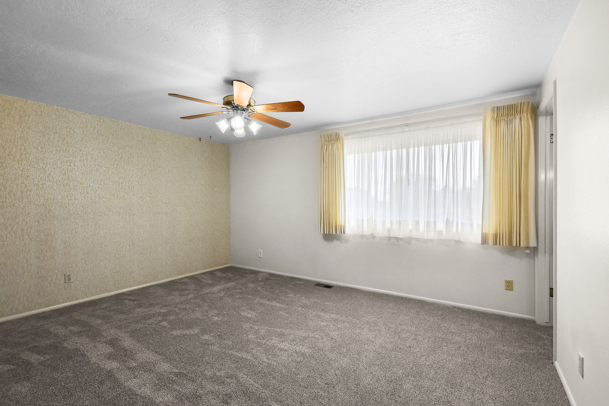Empty room with ceiling fan, carpet, and a textured ceiling