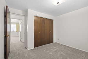 Unfurnished bedroom featuring light colored carpet, a closet, and a textured ceiling