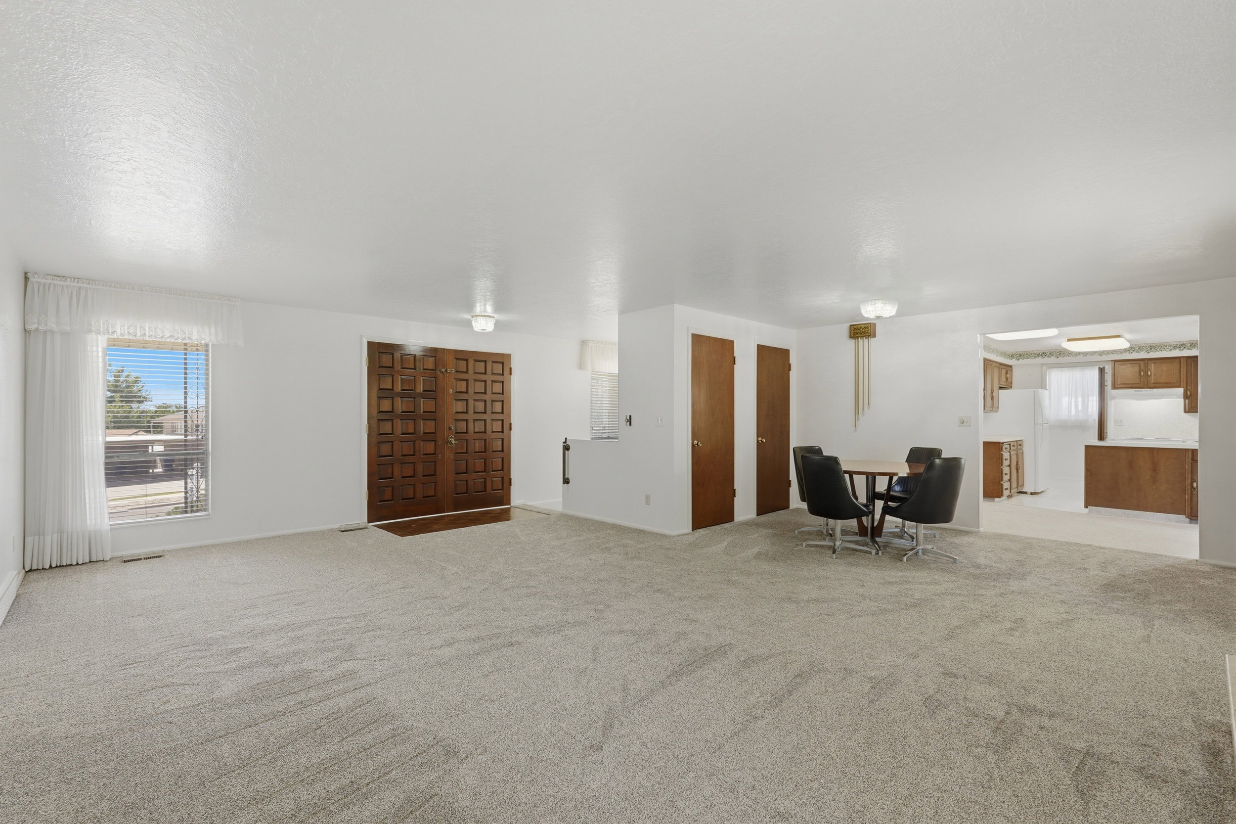 Spacious living area featuring light-toned carpeting and white walls