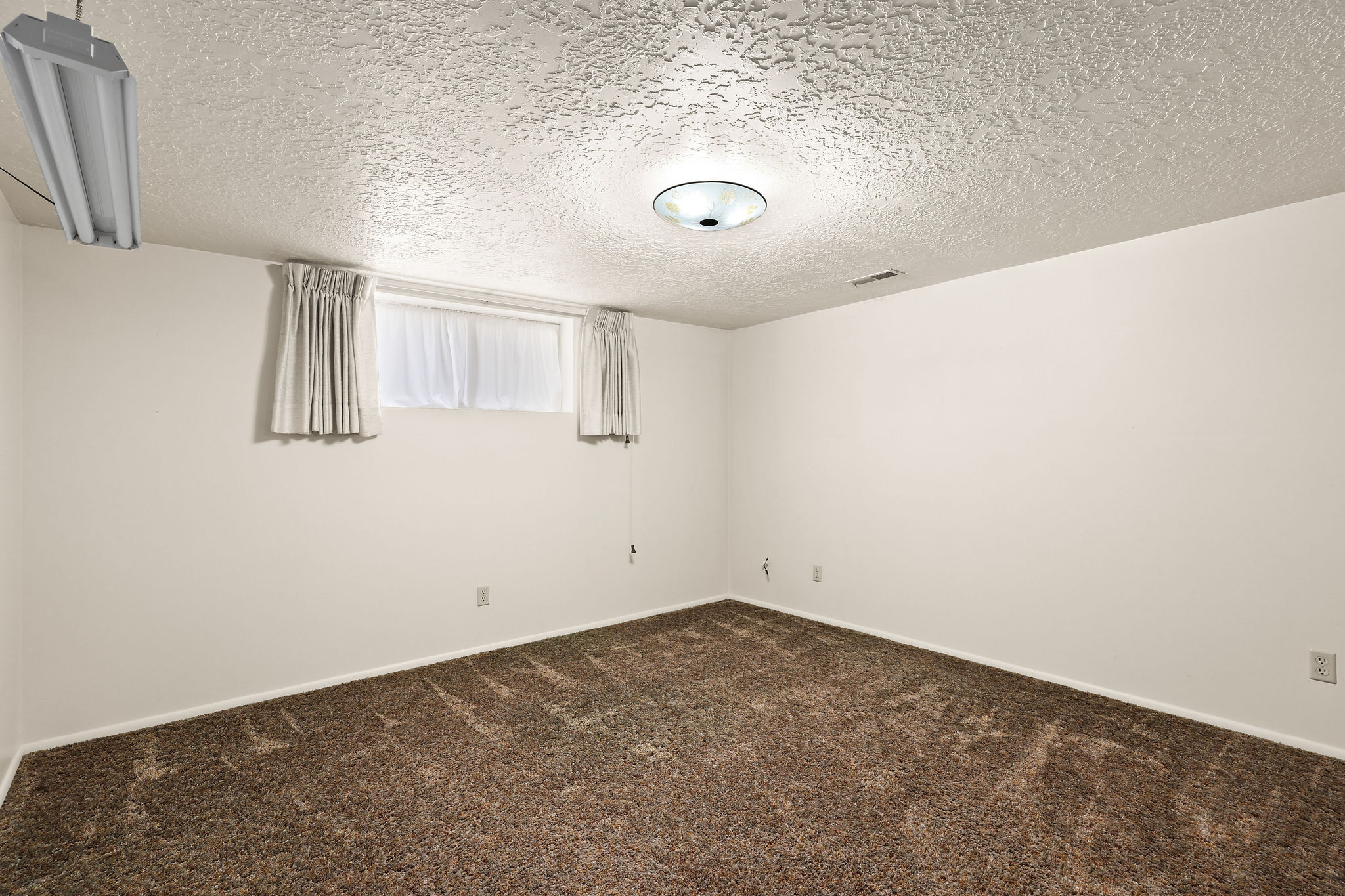 Unfurnished room featuring a textured ceiling and dark colored carpet