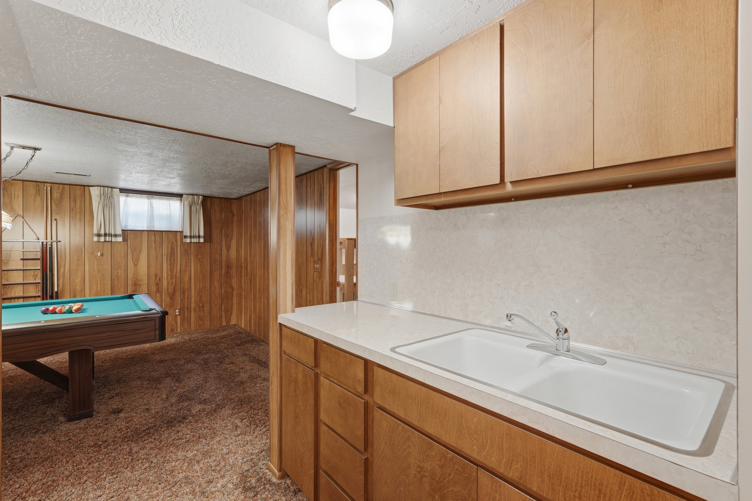 Lower level featuring a kitchenet with wood-finish cabinetry, a double basin sink, and a laminate countertop