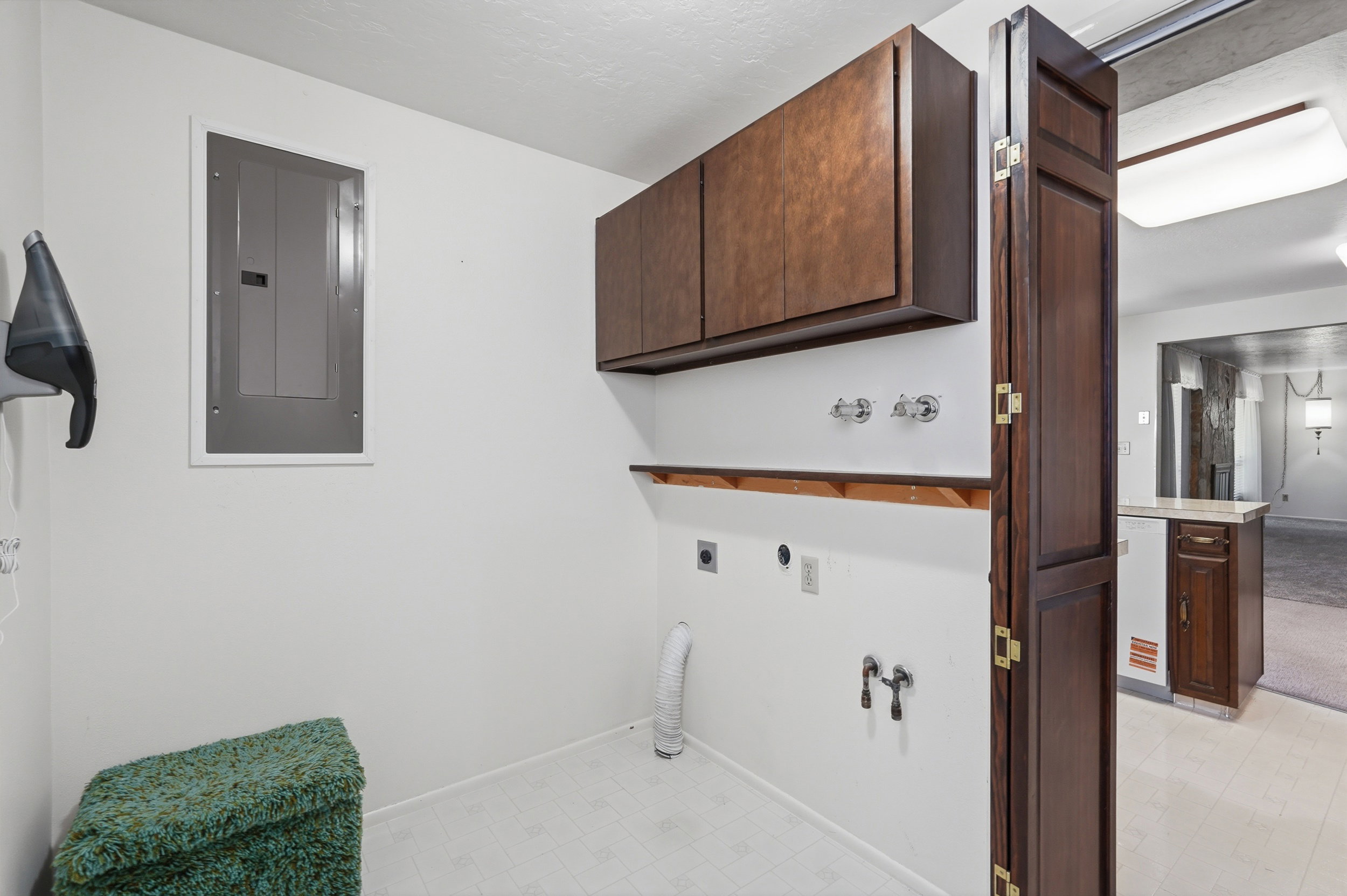 Laundry area featuring upper cabinetry, a built-in shelf, and appliance hookups/mudroom adjacent to garage.