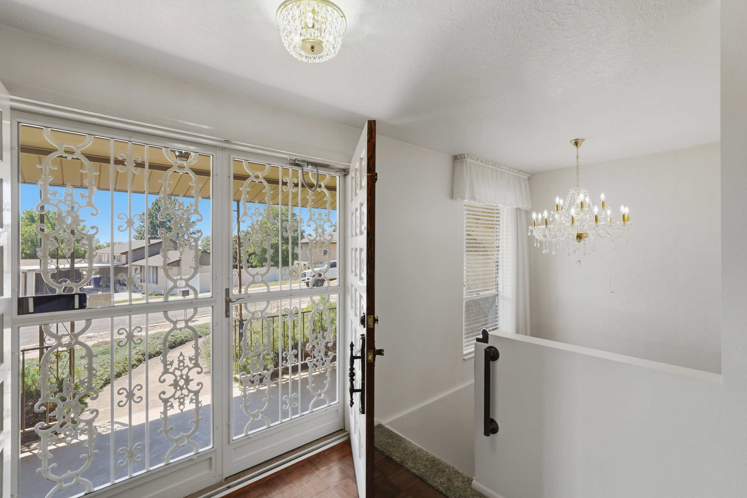 Entryway featuring security doors with decorative scrolling, a wood-finish floor, and a chandelier