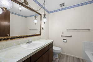 Bathroom with vanity, dark wood-type flooring, and a bath