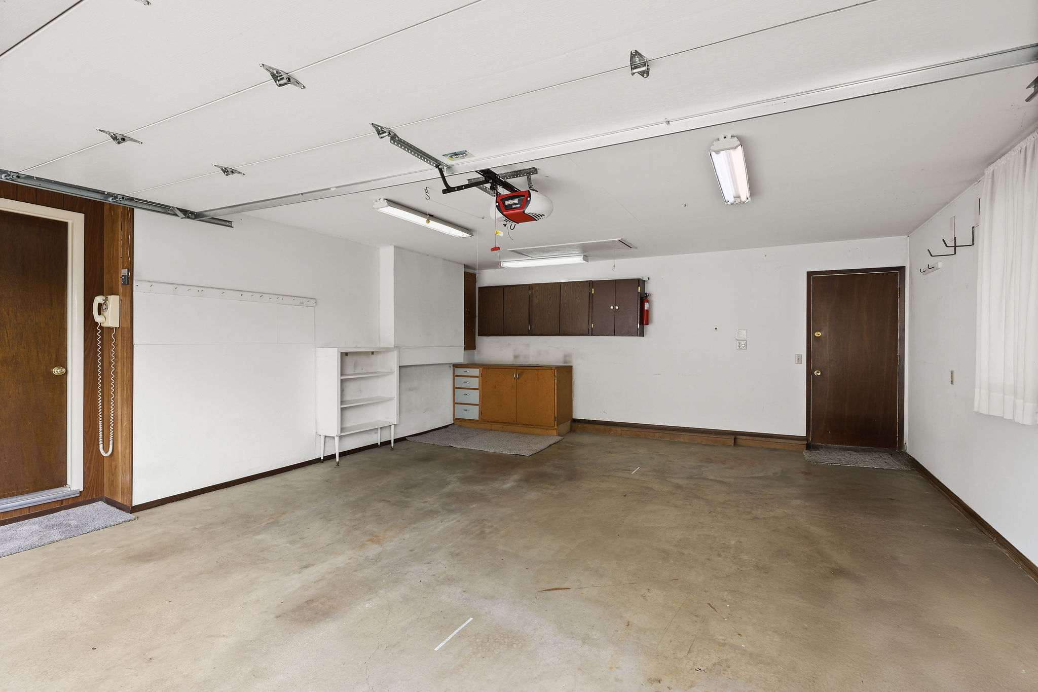 Garage with baseboards and a garage door opener and workbench.