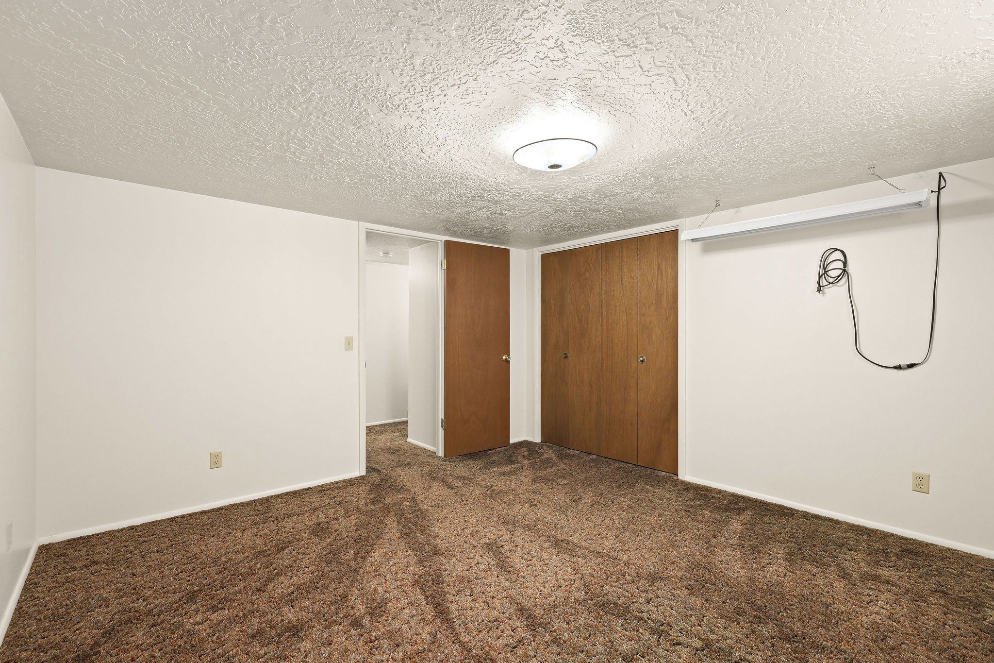 Unfurnished bedroom with a textured ceiling, dark colored carpet, and a closet