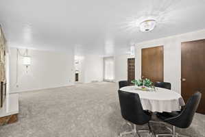 Carpeted dining area with a textured ceiling and baseboards