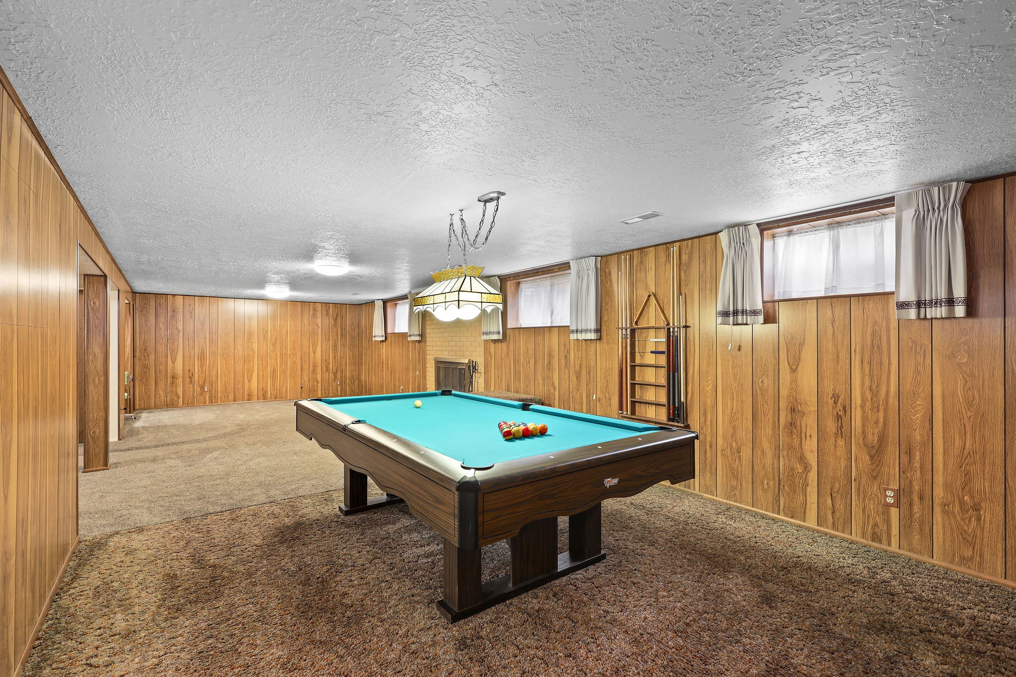 Rec room featuring carpet floors, a textured ceiling, billiards table, and wood walls. Billiards table is included.