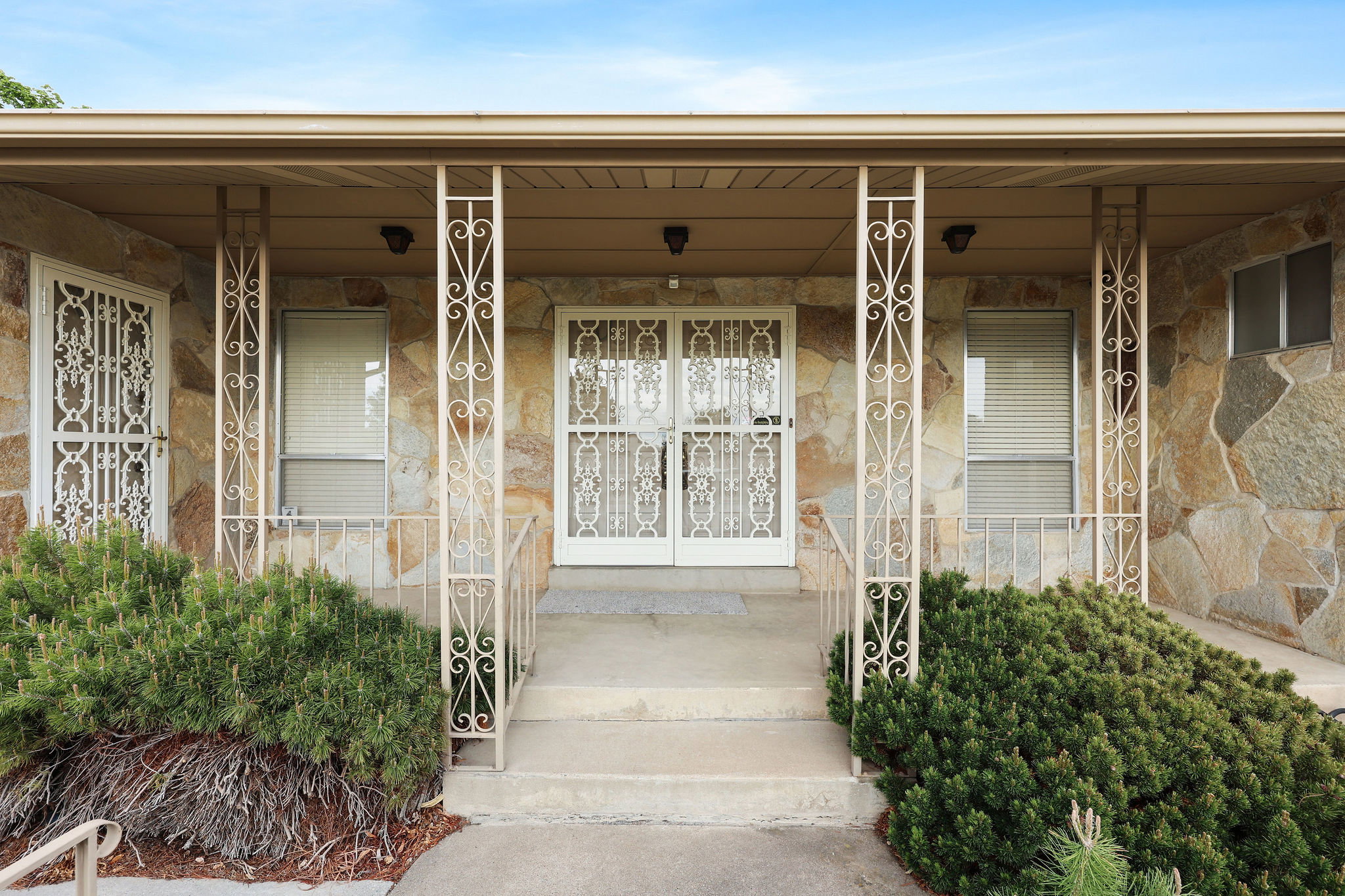 View of exterior entry featuring a porch with security doors and stone
