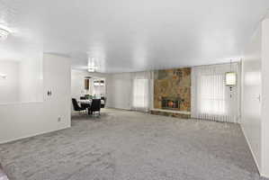 Carpeted living room featuring a textured ceiling and a fireplace