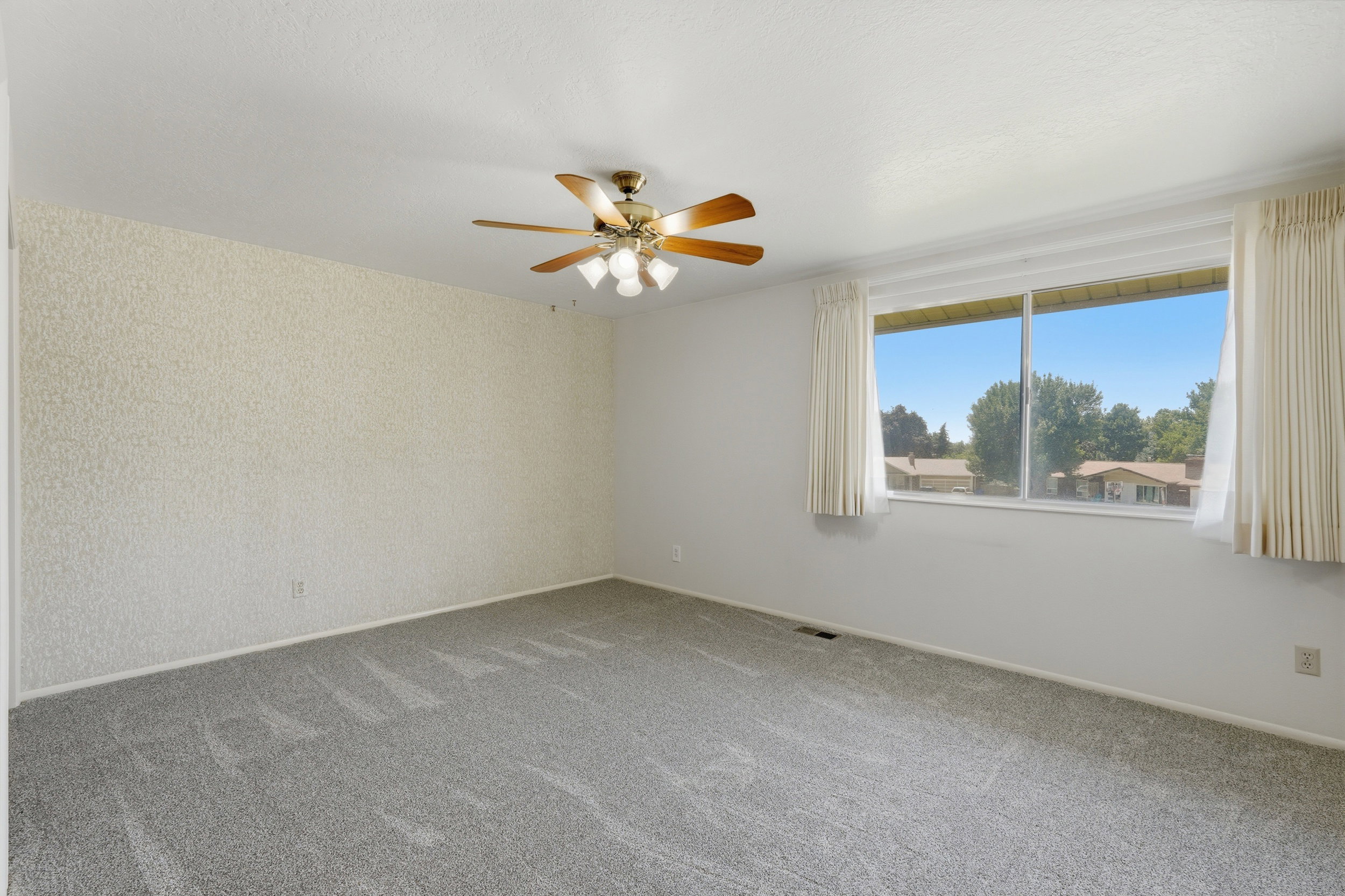 Spacious room featuring light gray carpet flooring and a ceiling fan with integrated lighting