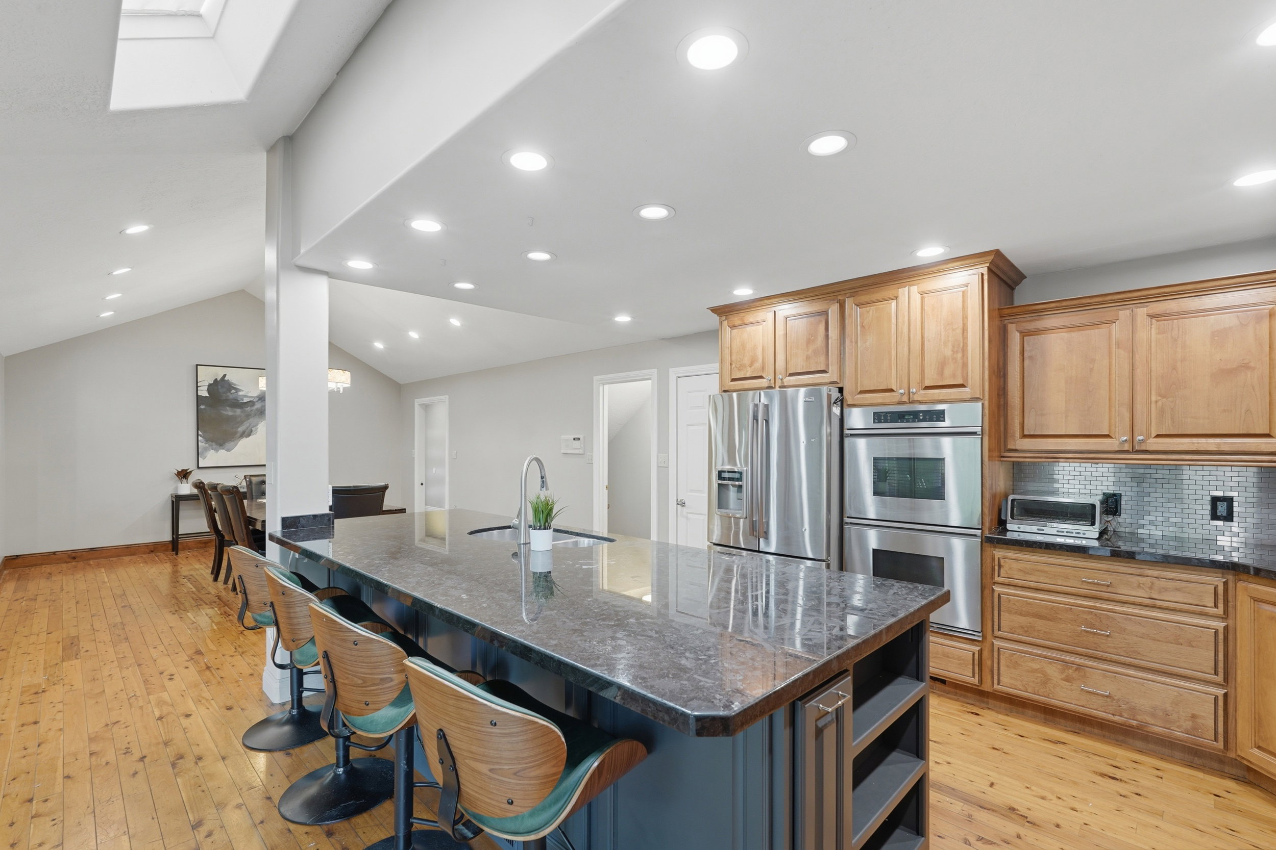 Dual tone kitchen featuring dual tone cabinets, 10' island,  granite counters, recessed lighting, and stainless steel appliances