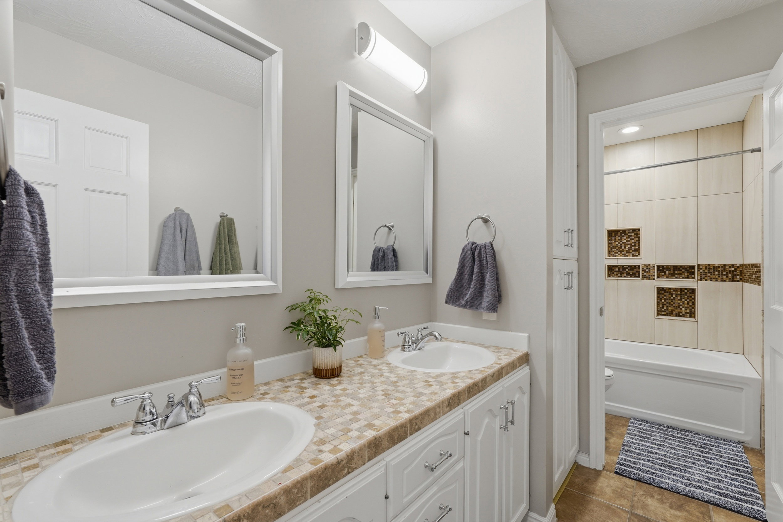 Main Floor Full bath featuring double vanity,  shower combination, and light tile patterned flooring