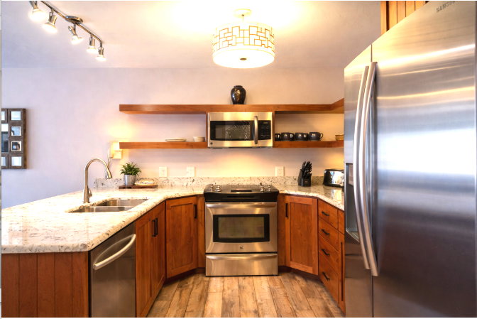 Kitchen with open shelves, stainless steel appliances, a peninsula, light stone countertops, and wood finish cabinetry