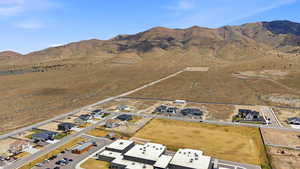 Aerial view of property and surrounding area featuring a mountain backdrop and nearby suburban area