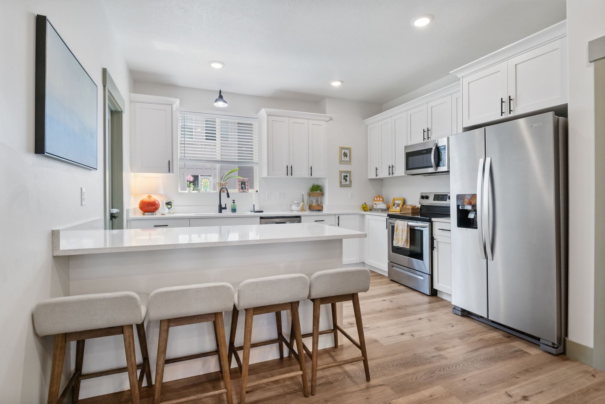 Kitchen featuring stainless steel appliances, a kitchen bar, a peninsula, white cabinets, and recessed lighting