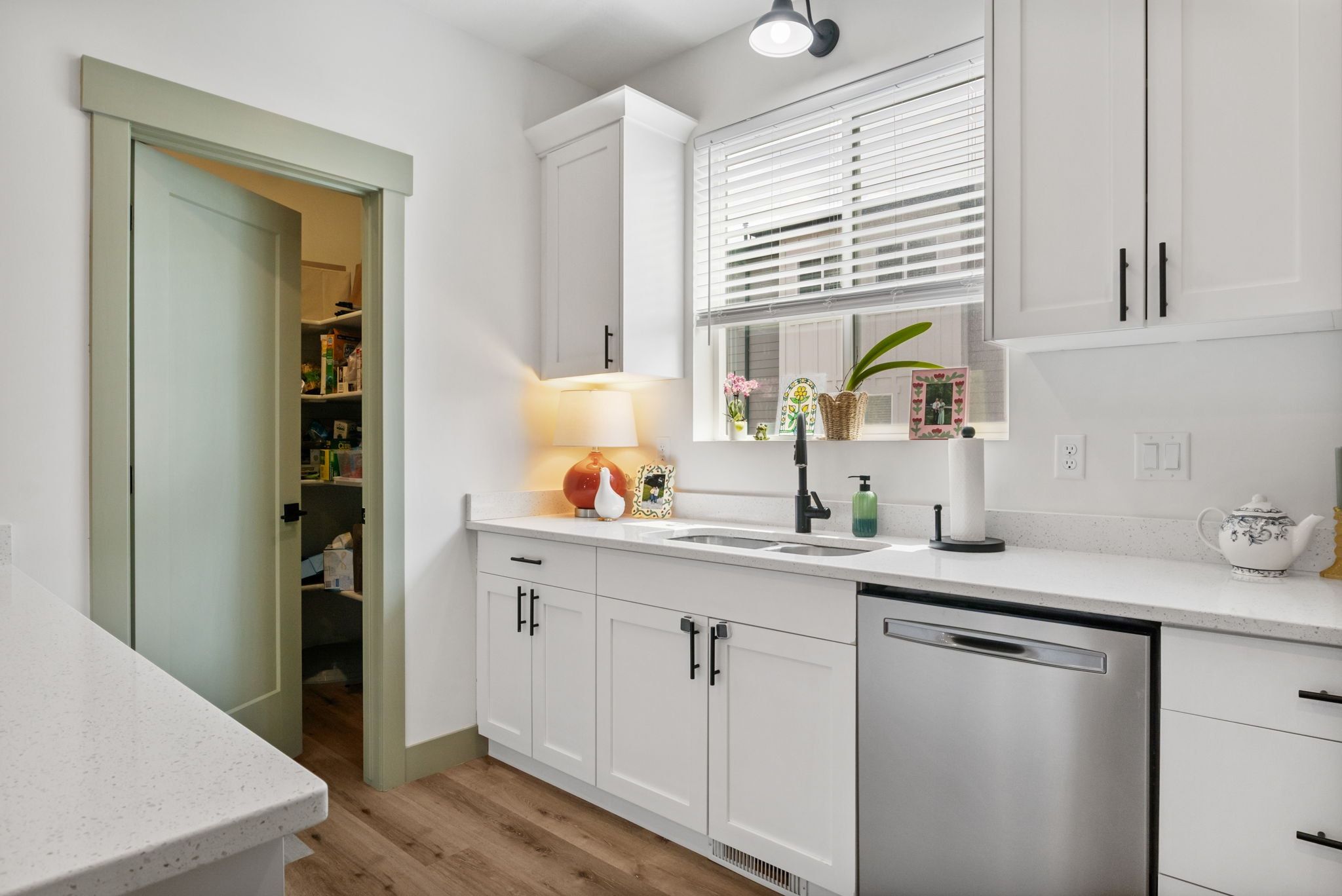 Kitchen featuring white cabinetry, dishwasher, light wood-style flooring, and light stone counters