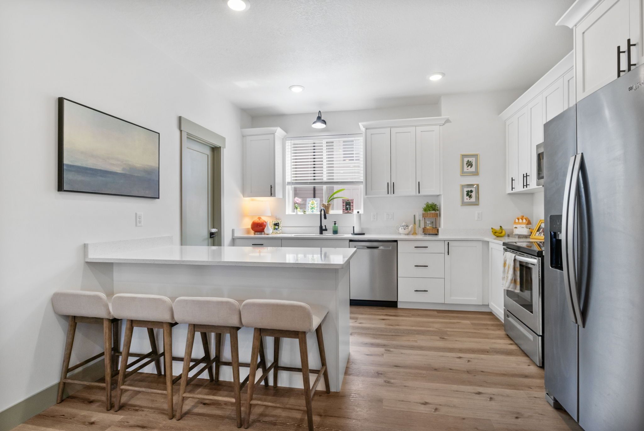 Kitchen with a breakfast bar area, stainless steel appliances, white cabinetry, a peninsula, and recessed lighting