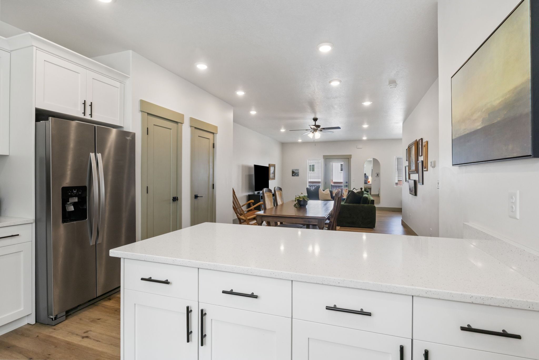 Kitchen with white cabinetry, stainless steel fridge with ice dispenser, light wood finished floors, open floor plan, and recessed lighting