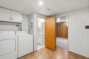 Laundry area with washing machine and clothes dryer, wooden walls, and cabinet space