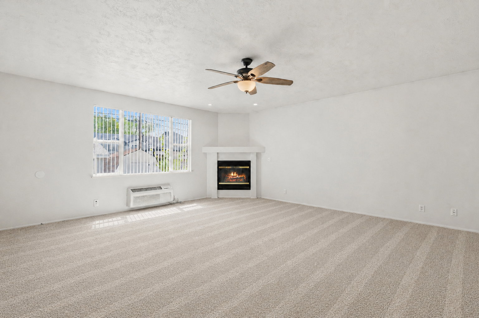 Unfurnished living room featuring light carpet, ceiling fan, a glass covered fireplace, and a textured ceiling