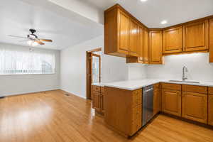 Kitchen featuring wood finish cabinetry, ceiling fan, light wood-style floors, and stainless steel dishwasher