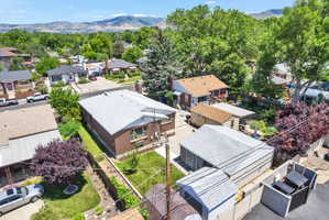 Aerial perspective showcasing a brick residence with a light-colored roof, surrounded by mature trees