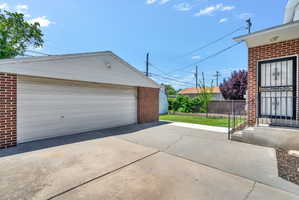 Detached garage with a white overhead door, brick facade, and white soffit and fascia