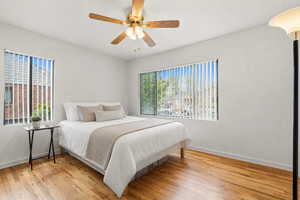 Bedroom featuring light wood finished floors, ceiling fan, and multiple windows