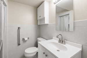 Bathroom with vanity, a shower with shower curtain, and tile walls