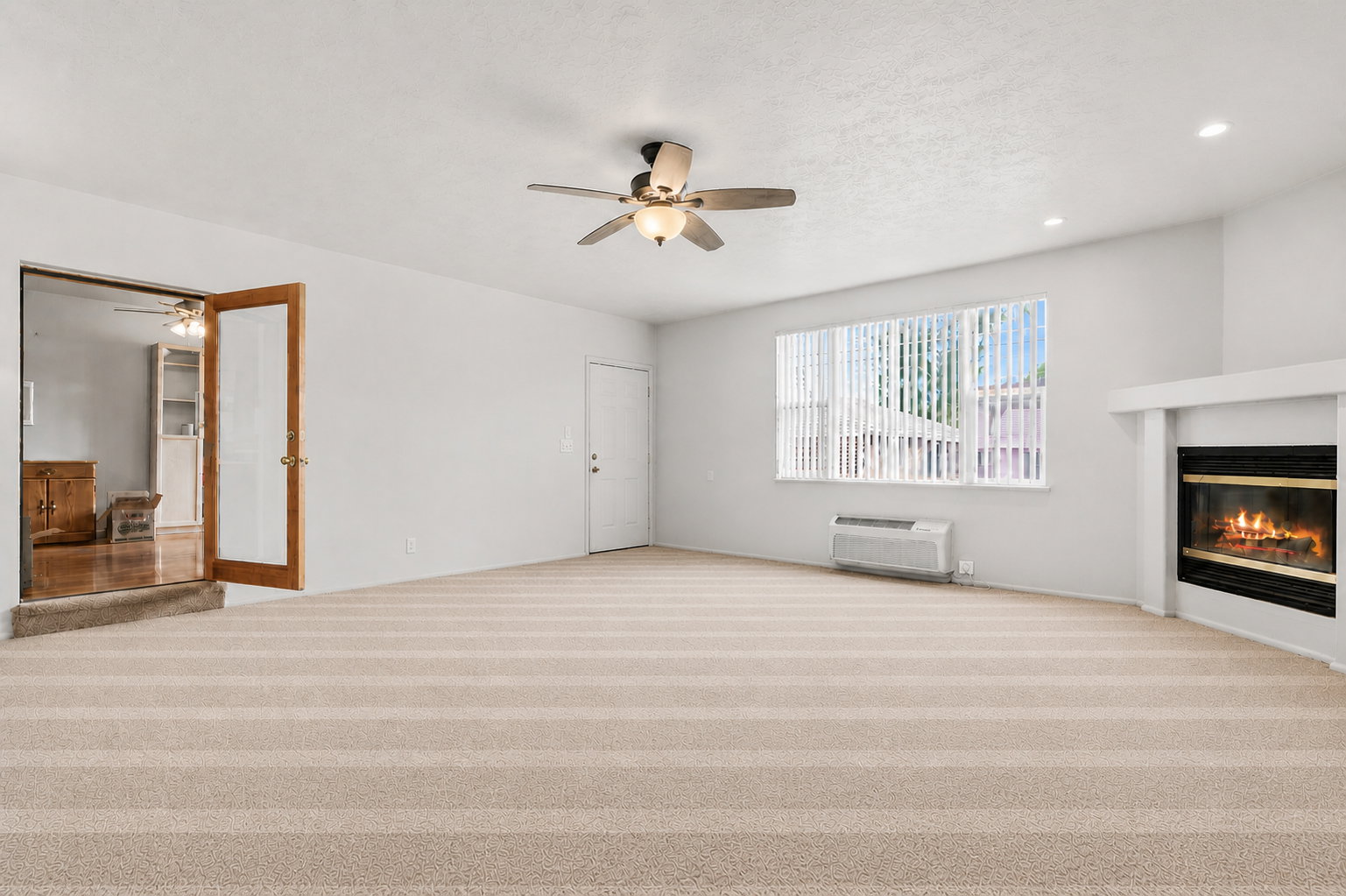 Unfurnished living room featuring a ceiling fan, light colored carpet, a glass covered fireplace, recessed lighting, and a textured ceiling