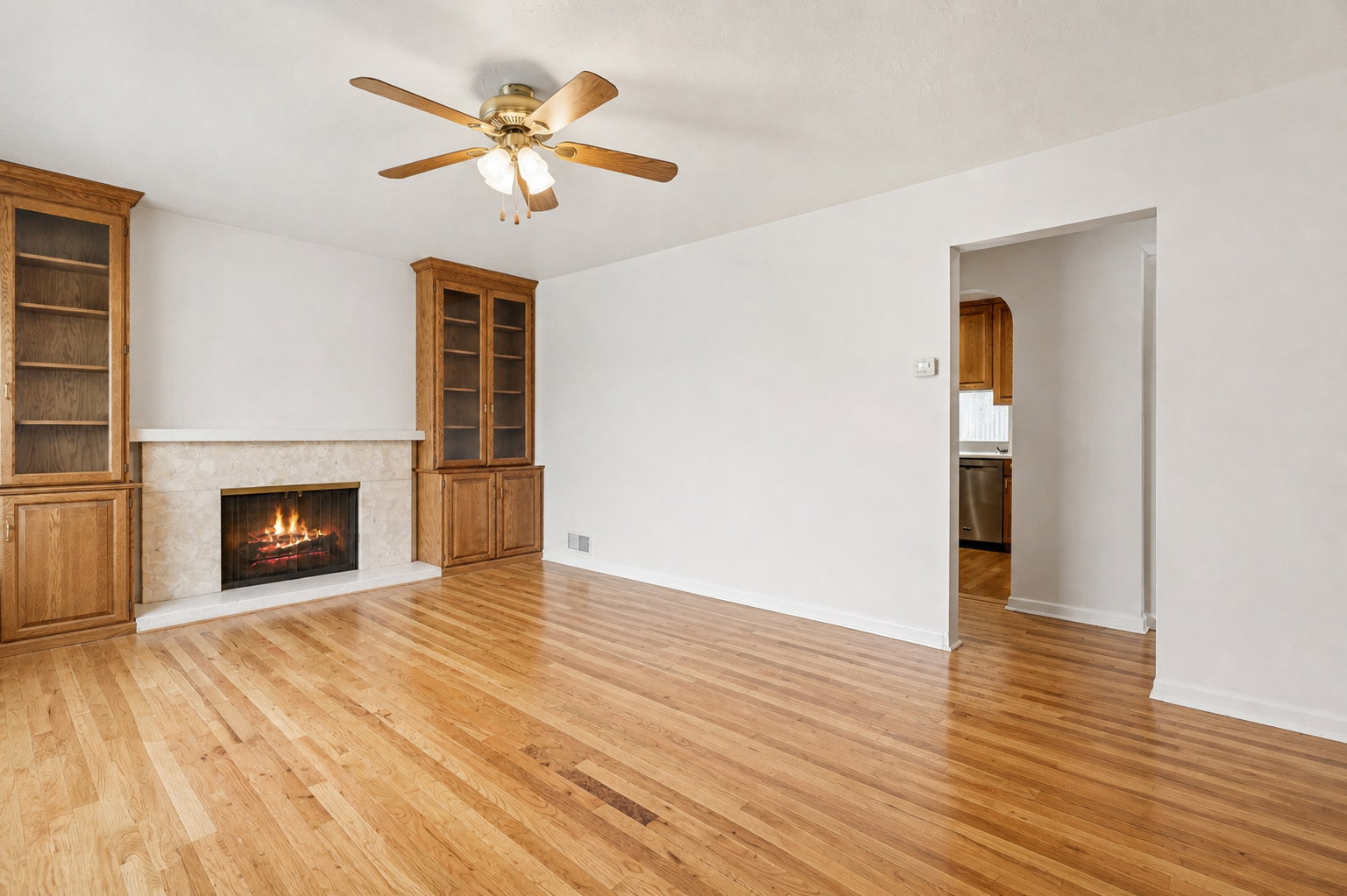 Unfurnished living room with arched walkways, ceiling fan, light wood-style floors, and a high end fireplace
