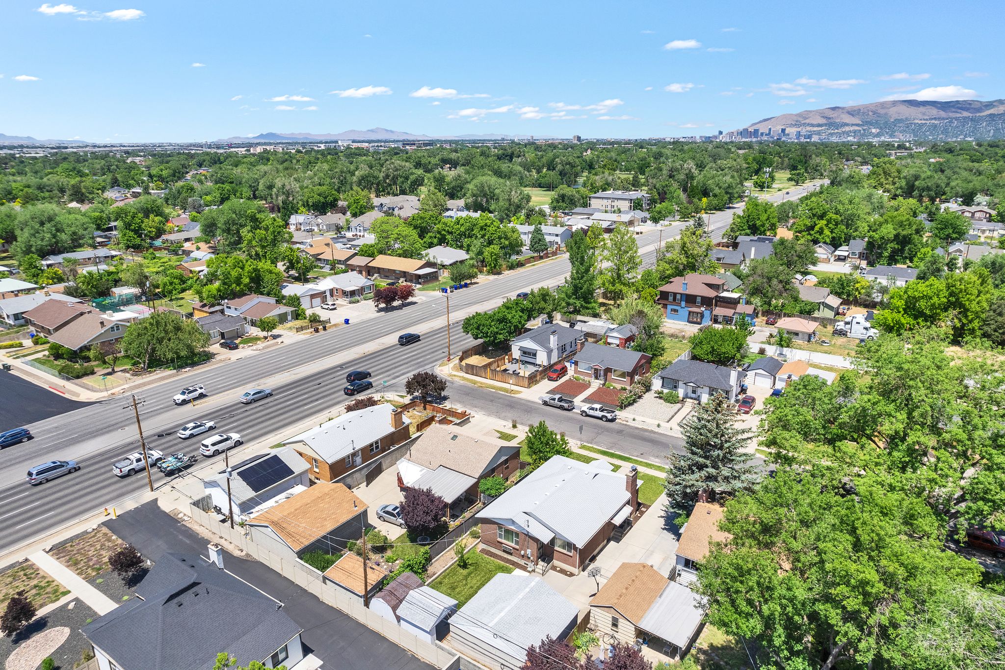 Residential neighborhood with mature trees, established properties, and a visible mountain range in the distance