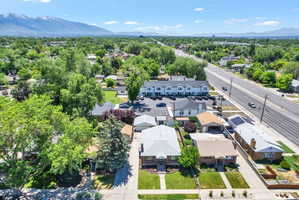 Aerial perspective showcasing residential properties with mature trees, a multi-lane road, and distant mountains