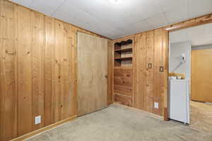 Spare room featuring wood walls, carpet, and washer / dryer