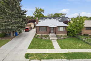 Bungalow with brick siding, a chimney, and a shingled roof