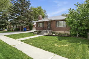 Bungalow with a chimney, a front lawn, brick siding, and roof with shingles