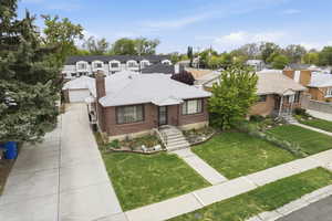 View of front of property featuring a front lawn, brick siding, a chimney, a shingled roof, and a residential view