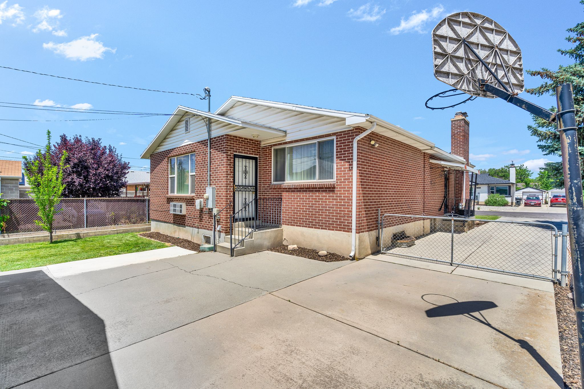 Brick exterior with white trim, featuring a concrete driveway and an entryway with security screen door
