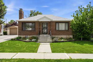View of front of property featuring an outdoor structure, a front lawn, a chimney, and a detached garage