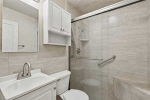 Full bath featuring vanity, tile walls, and a shower stall