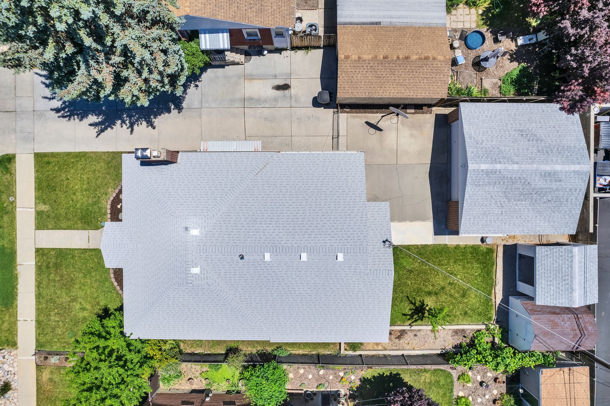 Shingle roof home featuring a concrete driveway, detached garage with a shingle roof, paved patio area, and a stone walkway