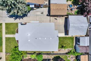 Shingle roof home featuring a concrete driveway, detached garage with a shingle roof, paved patio area, and a stone walkway
