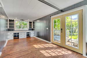 Entryway featuring french doors, built in study area, wood-type flooring, built in shelves, and wood walls