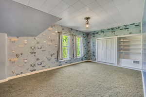 Unfurnished bedroom with carpet, a closet, and wallpapered walls