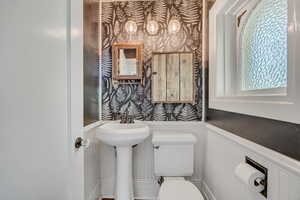 Bathroom with wallpapered walls and wainscoting