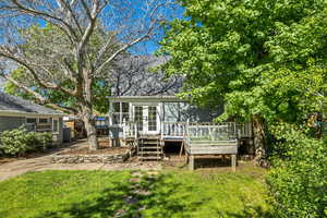 Rear view of property with a deck, a lawn, and a shingled roof