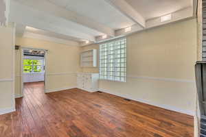 Spare room featuring dark wood-style floors, beam ceiling, and ornamental molding