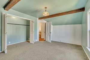 Unfurnished bedroom with vaulted ceiling with beams, light colored carpet, and a closet
